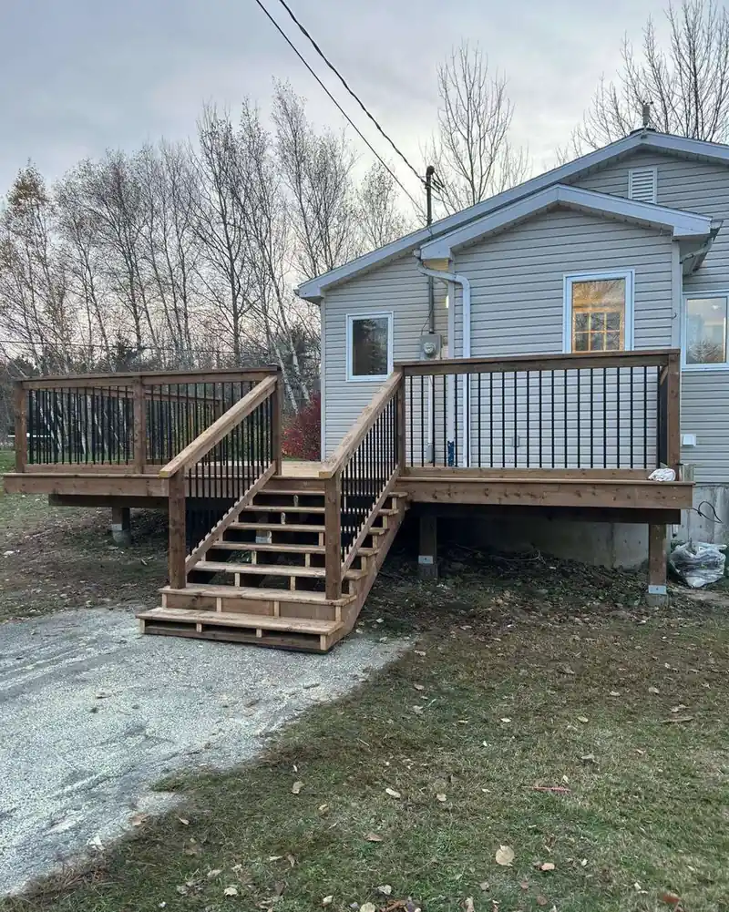 New back steps and a black picket rail on a pale blue house.