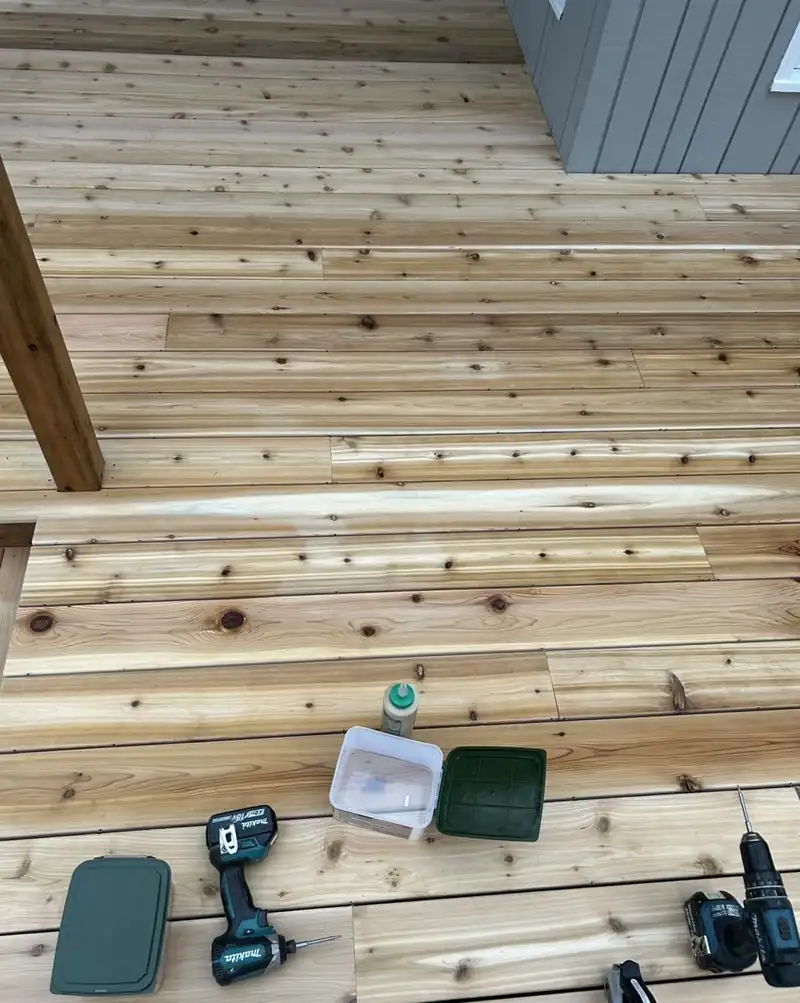 Fresh cedar decking being screwed down, drills and screws sitting on the boards.