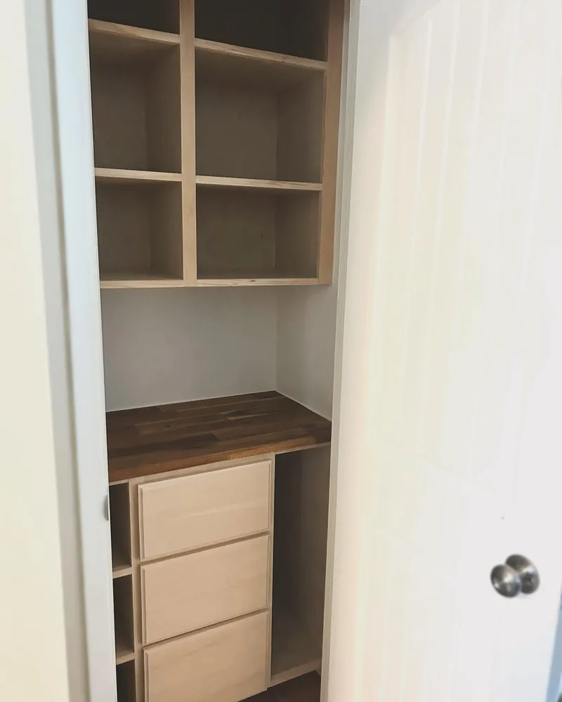 A built-in closet with open shelving and a run of drawers.