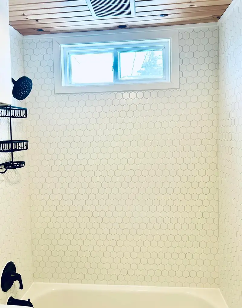 A tiled tub surround with a small window set into the wall above.
