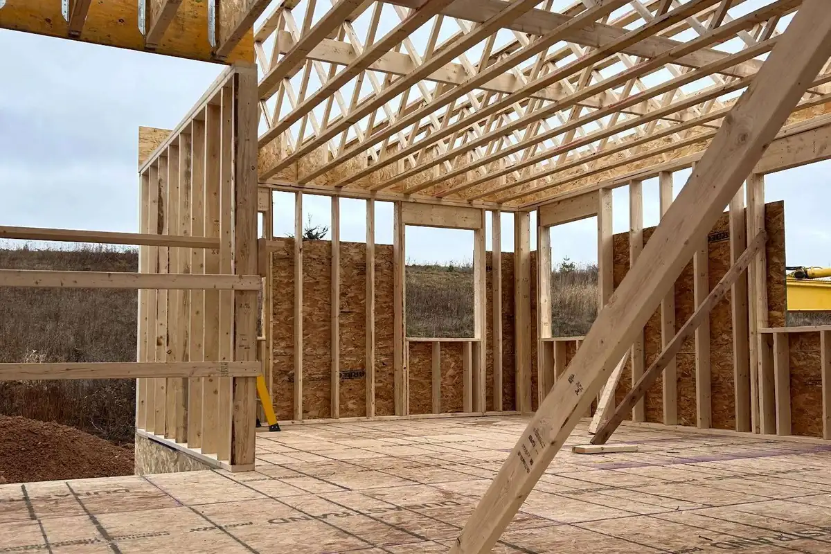 Standing on the subfloor of a Tipple build with the exterior walls up and open-web floor trusses running overhead.